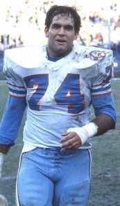 Bruce Matthews in Houston Oilers uniform, covered in dirt, carrying his helmet in his hand.