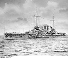 A battleship at sea with a smaller boat alongside