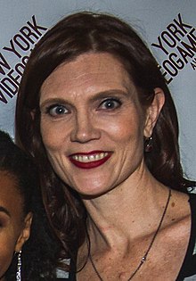 A 44-year-old with brown hair smiling at the camera.