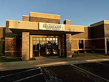 The front of the Nixa branch library is depicted. The library is brick and immediately meets a parking lot.