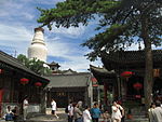 A temple in the mountains with a white stupa in the background