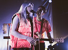 A man plays a guitar while a woman sings into a microphone.