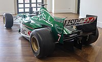 a green open wheeled racing car in a museum
