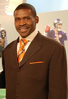Michael Irvin smiling and from about the waste up in a brown suit.