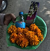 A typical basket of offerings, containing desi daru (country liquor), a pack of incense sticks and marigold flowers