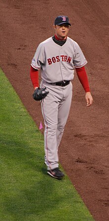A man in a gray baseball uniform with a navy cap