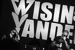 Wisin & Yandel, performing in front of a large sign with their names