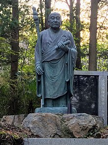 A statue of Ennin, an important disciple of Saicho with blue sky in the background, facing right