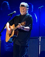 Rock singer Bob Seger, strumming an acoustic guitar and singing into a microphone