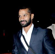 A bearded Indian man wearing a white shirt with a black blazer