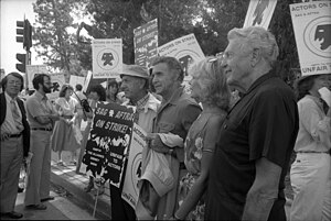 Photograph of a crowd of people standing at an intersection holding various signs that say things like, "Actors on Strike" and "Unfair to Actors"