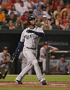 Ken Griffey, Jr. batting as a Seattle Mariner. In the background is the Mariner's dugout.