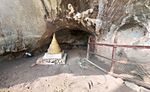 A Buddhist stupa in front of a cave entrance