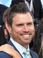 A sideview of a man in a suit and tie smiling at the camera.