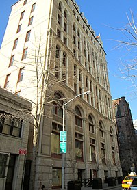 A ten-story building with a light-toned brick façade, viewed from street level