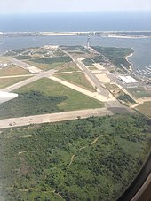 Aerial view of runways amid a grassy field, with a bay in the background