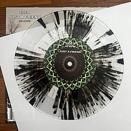 Top corner of the album's back side sleeve, visible beside the record displaying its transparent design with black splatter.