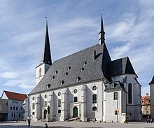 A pale grey church with white detail, dark roof, and a steeple