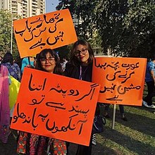 Two smiling women with three signs