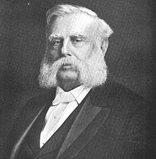 Photograph of Gary in a suit with white hair and white mutton chops beard