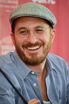 Aronofsky kneeling while holding a microphone