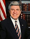 Man in business suit, American flag in background