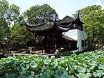 Chinese style pavilion near a pond with lotuses.