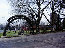 A colliery winding wheel sunk into the ground as a memorial