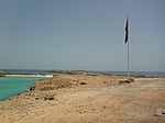 Rocky barren island with a flag pole