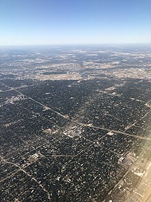 The path of tornado damage across North Dallas from the air the following morning. Looking southwest, the Dallas North Tollway is visible across the middle, and Dallas Love Field Airport is in the distance. The tornado travelled from top-right to bottom-left in this photo.