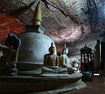 Stupa with sitting Buddhas around it in a cave with painted walls