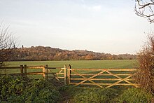 wooden gate with field and low hill beyond