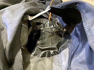 The inner taffeta lining cut open, where the device is aligned to the hole and secured with duct tape.