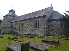 View of the south wall of the church and the apse, with gravestones in the foreground.