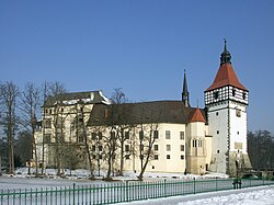 A castle with white walls, surrounded by water, on a bright winter day