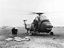 A helicopter on the ground with bags of supplies nearby