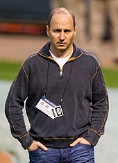 A man wearing a dark gray pullover with his hands in his jeans pockets