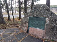 A placque affixed to a mound of granite.