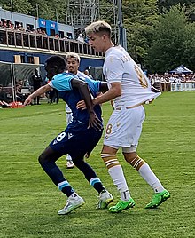 A player reach behind him to grab the jersey of his opponent