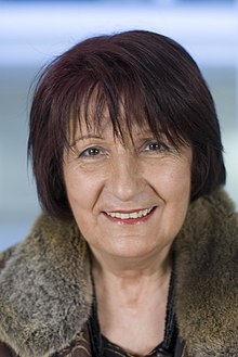 Portrait photo of a smiling woman with short brown hair wearing a coat with fur collar