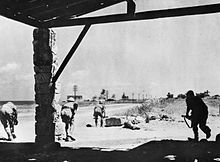 Soldiers advance under fire along a desert road towards a wireless station
