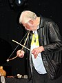 Man playing a heterochord musical bow, using his mouth for a resonator. Heterochords have strings made of a different material than the rigid part of the bow.[1]