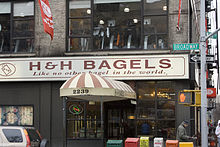 Storefront of H&H Bagel, awning at door and signage above reads "H&H Bagel - Like no other in the world."