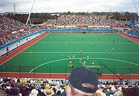 Hockey match in progress surrounded by thousands of fans in large stand
