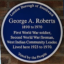 Circular blue plaque, with six lines of text reading "George A. Roberts / 1890 to 1970 / First World War soldier, / Second World War fireman, / West Indian Community Leader / lived here 1923 to 1970". Above those, the text "London Borough of Southwark" and below them, "Voted by the People".