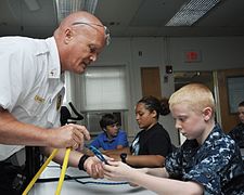 Naval Support Facility (NSF) Dahlgren fire department battalion chief Tracy Hall offers some knot-tying pointers to a Navy League cadet.