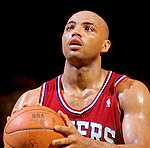 A basketball player, wearing a red jersey, is holding a basketball.