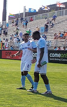 Shome talks with a teammate while walking on the pitch