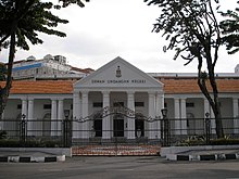 The front façade of the Penang State Assembly Building features columns supporting the pediment atop the portico.
