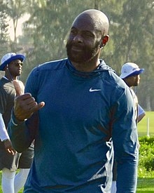 Jerry Rice in a blue Nike shirt making the hang loose hand gesture.